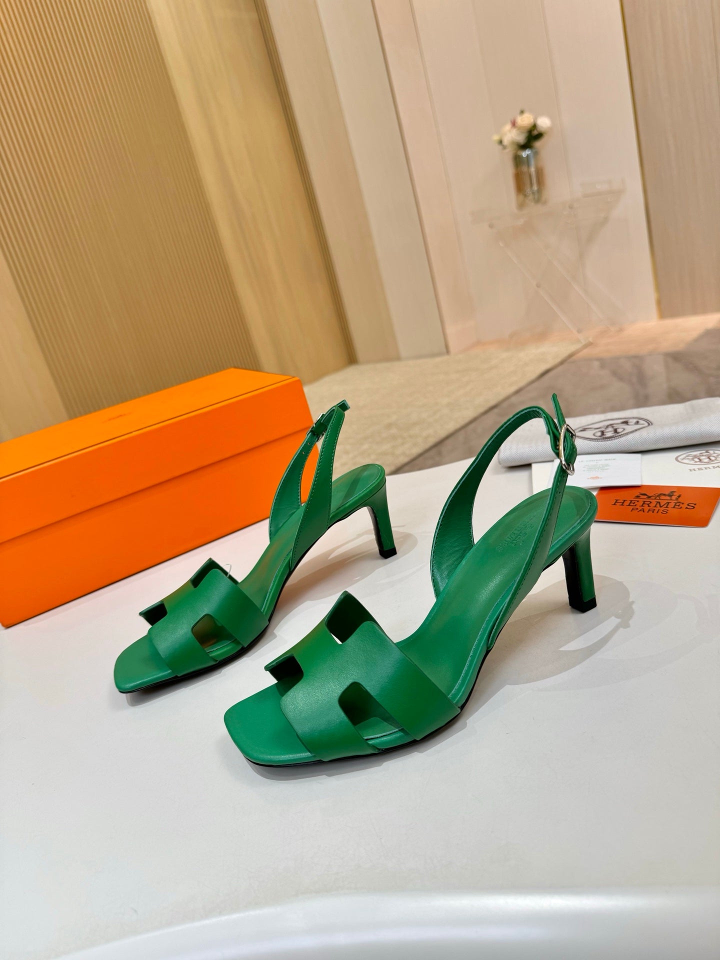 Pair of green leather heeled sandals with T-strap and slingback straps on display