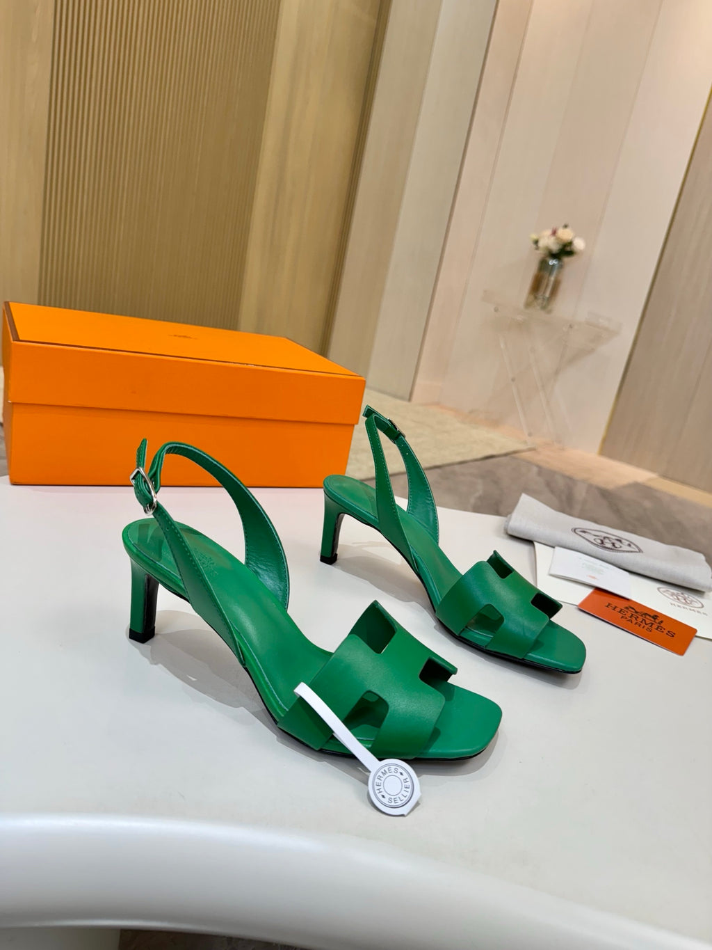 Green leather heeled sandals with T-strap and ankle slingback straps, on display