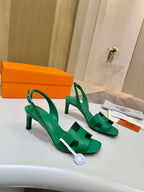 Green leather heeled sandals with T-strap and ankle slingback straps, on display