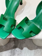 Close-up of green heeled sandals showing cutout T-strap and sculpted heel