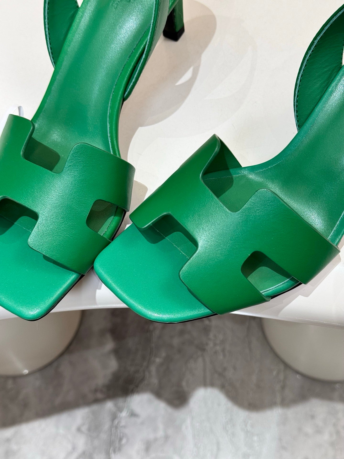 Close-up of green heeled sandals showing cutout T-strap and sculpted heel