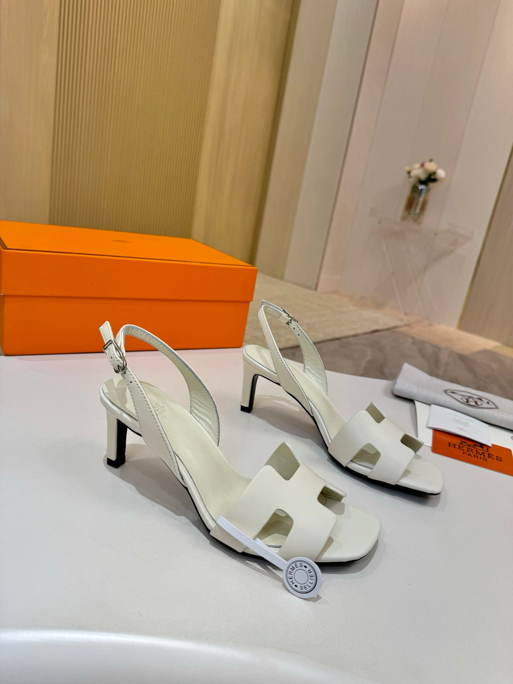 White heeled slingback sandals with cutout straps and round charm detail