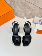 Pair of black heeled sandals with open toe and wide straps, leather-look finish