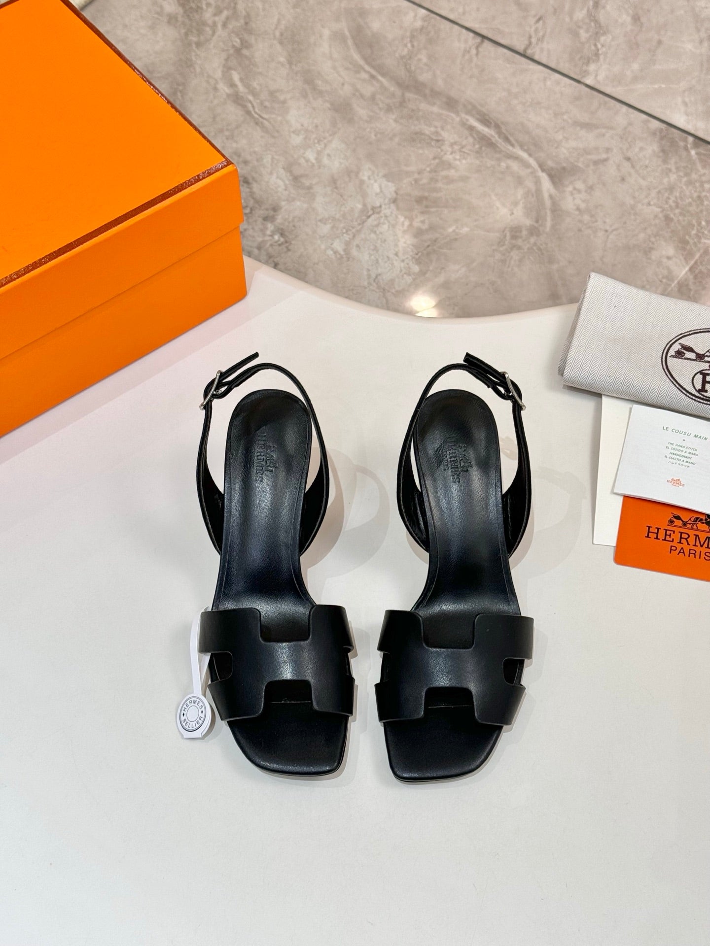 Pair of black heeled sandals with open toe and wide straps, leather-look finish