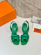 Green open-toe heeled sandals with ankle straps, laid on a white surface