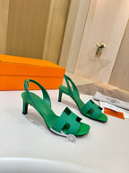 Pair of green open-toe heeled sandals with ankle strap and wide front straps