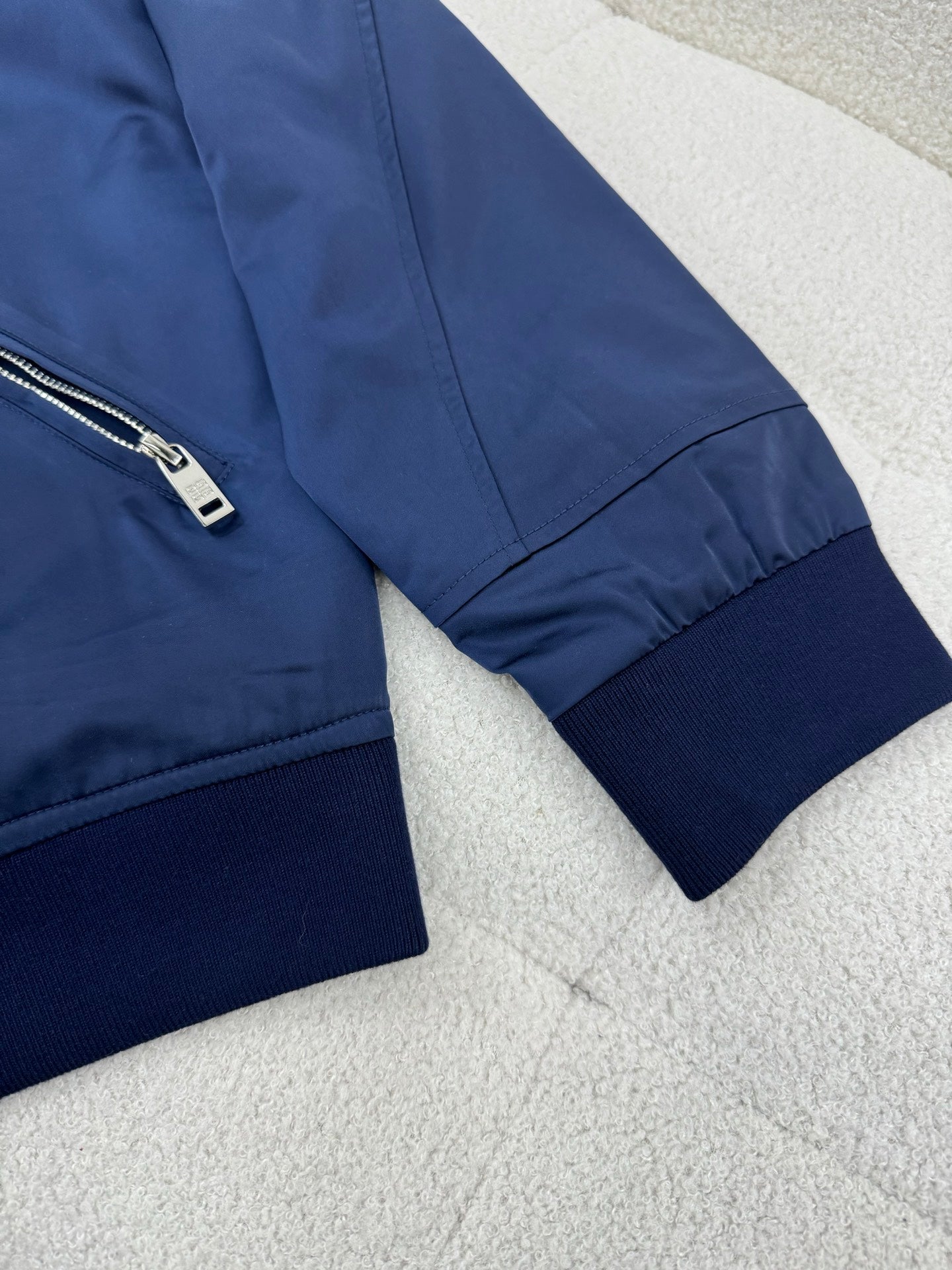 Dark blue bomber jacket sleeve with ribbed cuff and side zip pocket