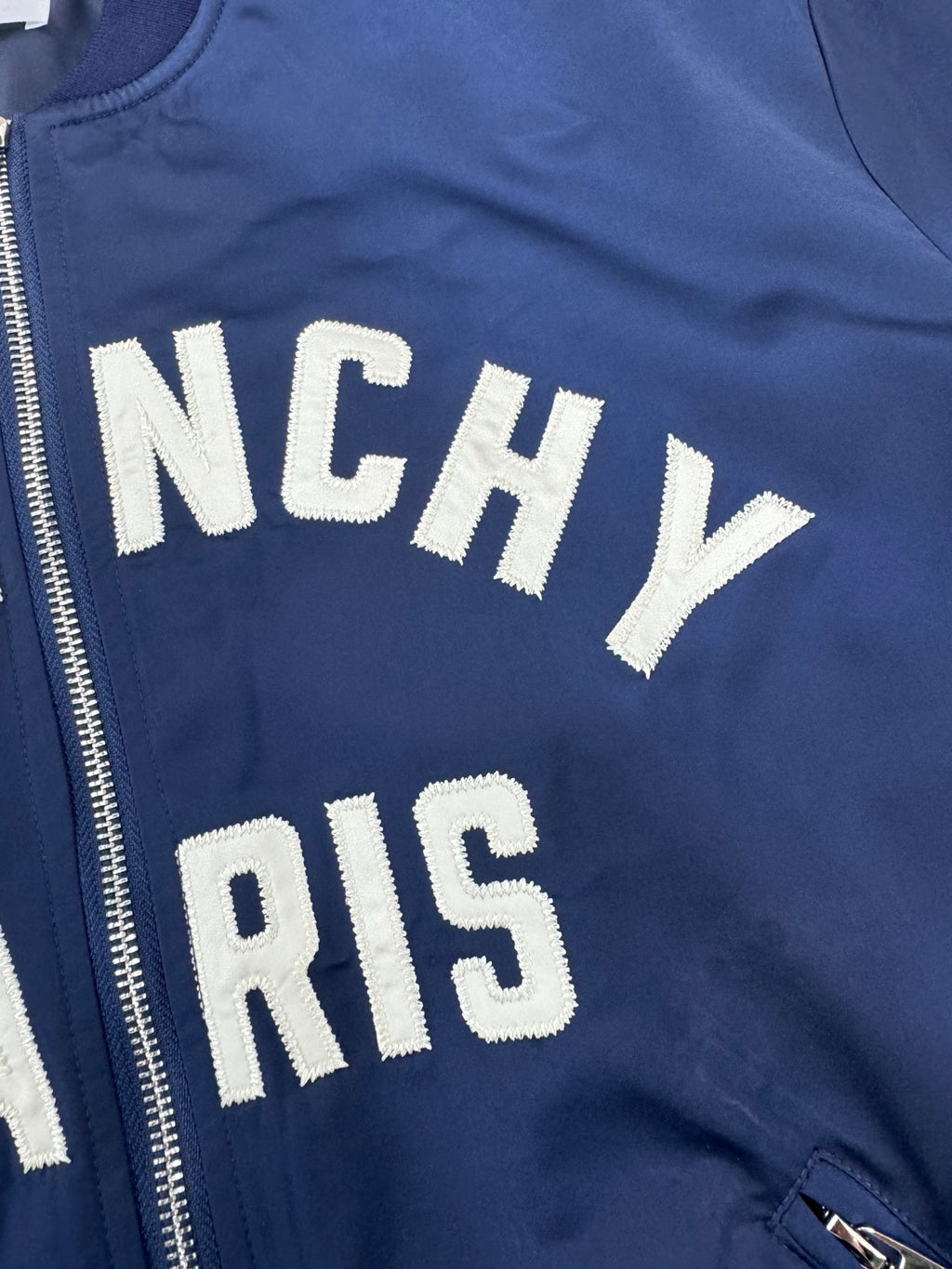 Dark blue bomber jacket zip front with partial "NCHY" and "PARIS" lettering