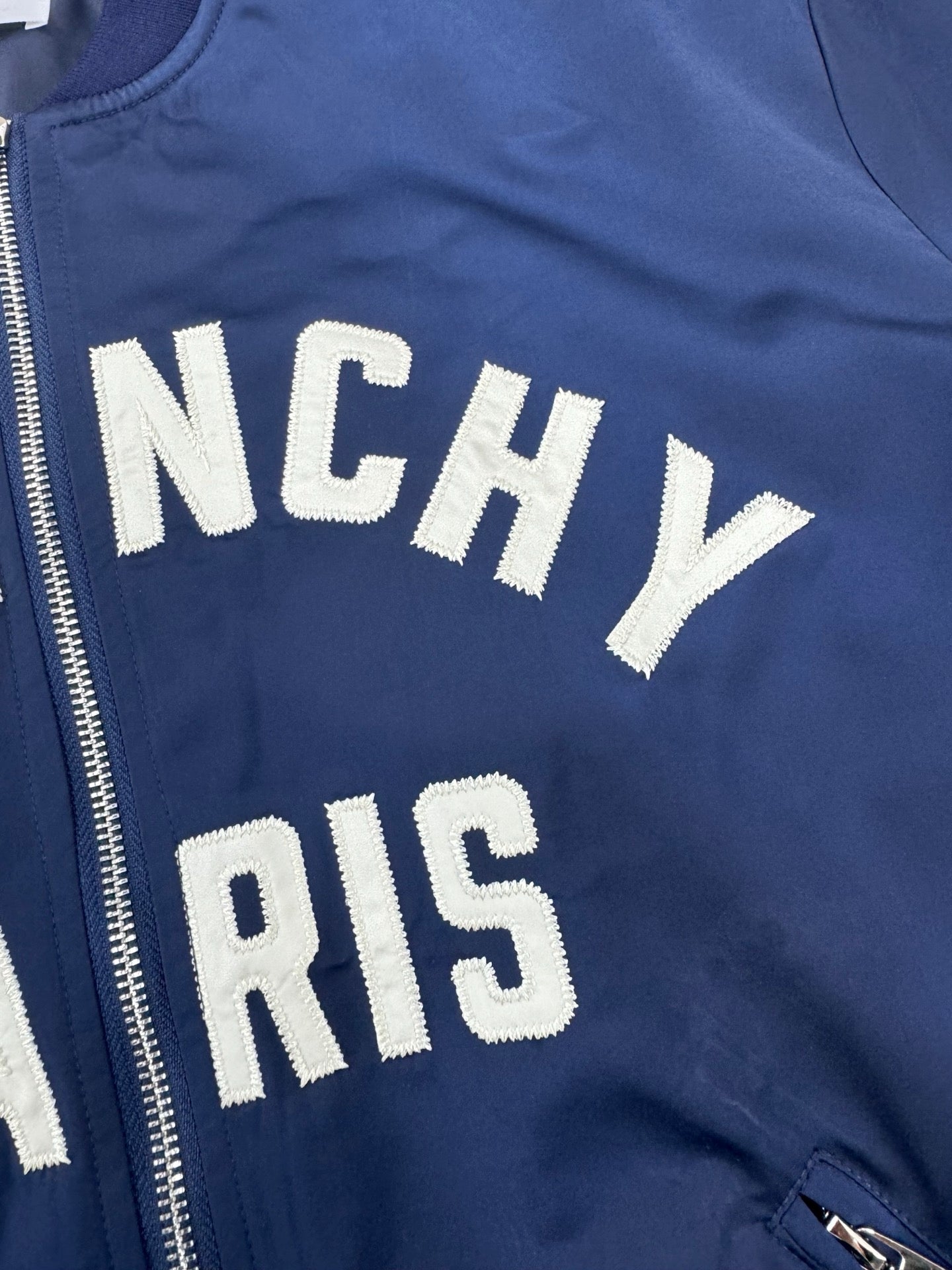 Dark blue bomber jacket zip front with partial "NCHY" and "PARIS" lettering