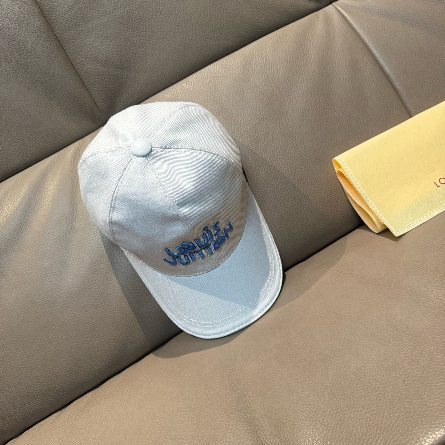 Louis Vuitton white cap with blue logo, side view with round top button