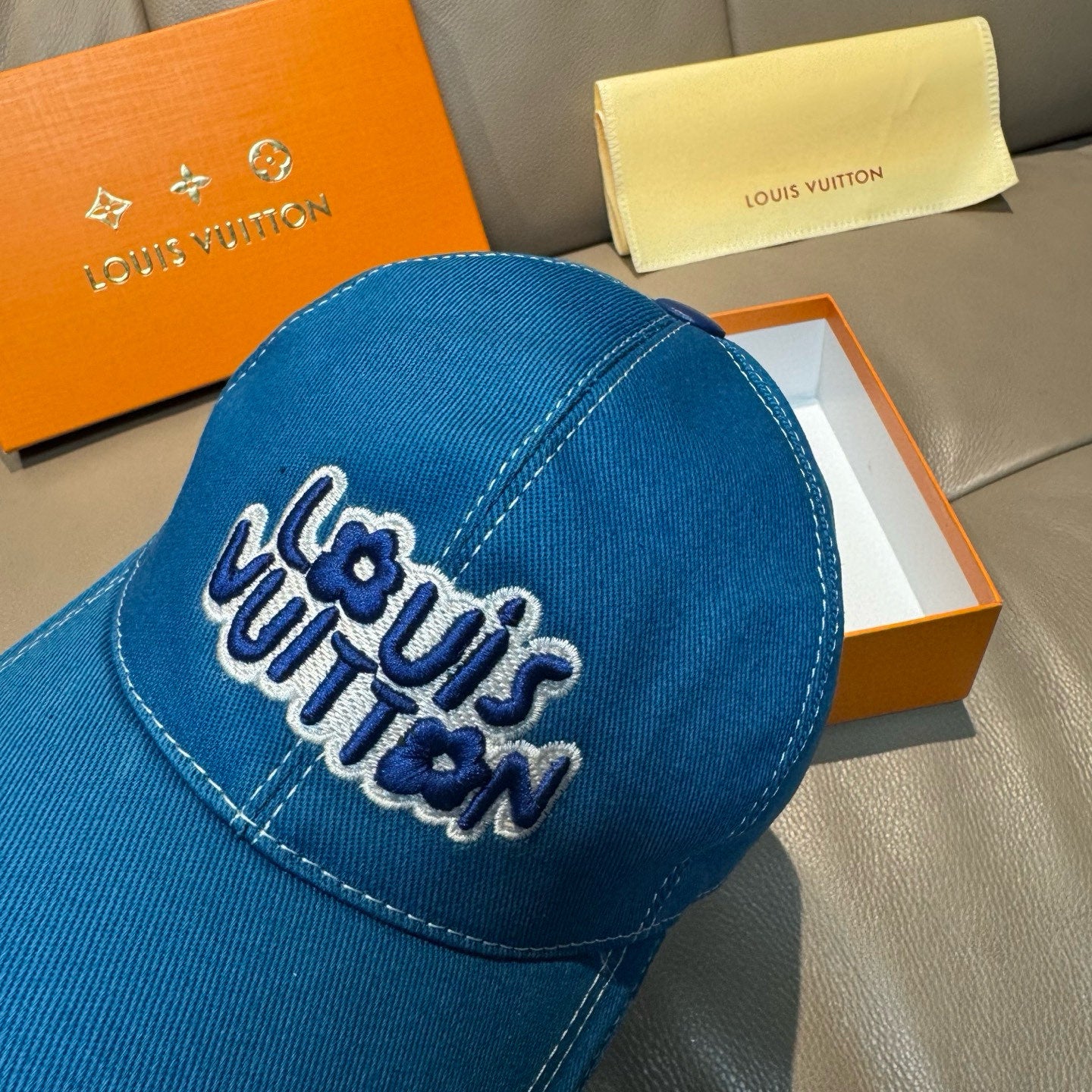 Blue denim cap close-up with embroidered Louis Vuitton logo on the front