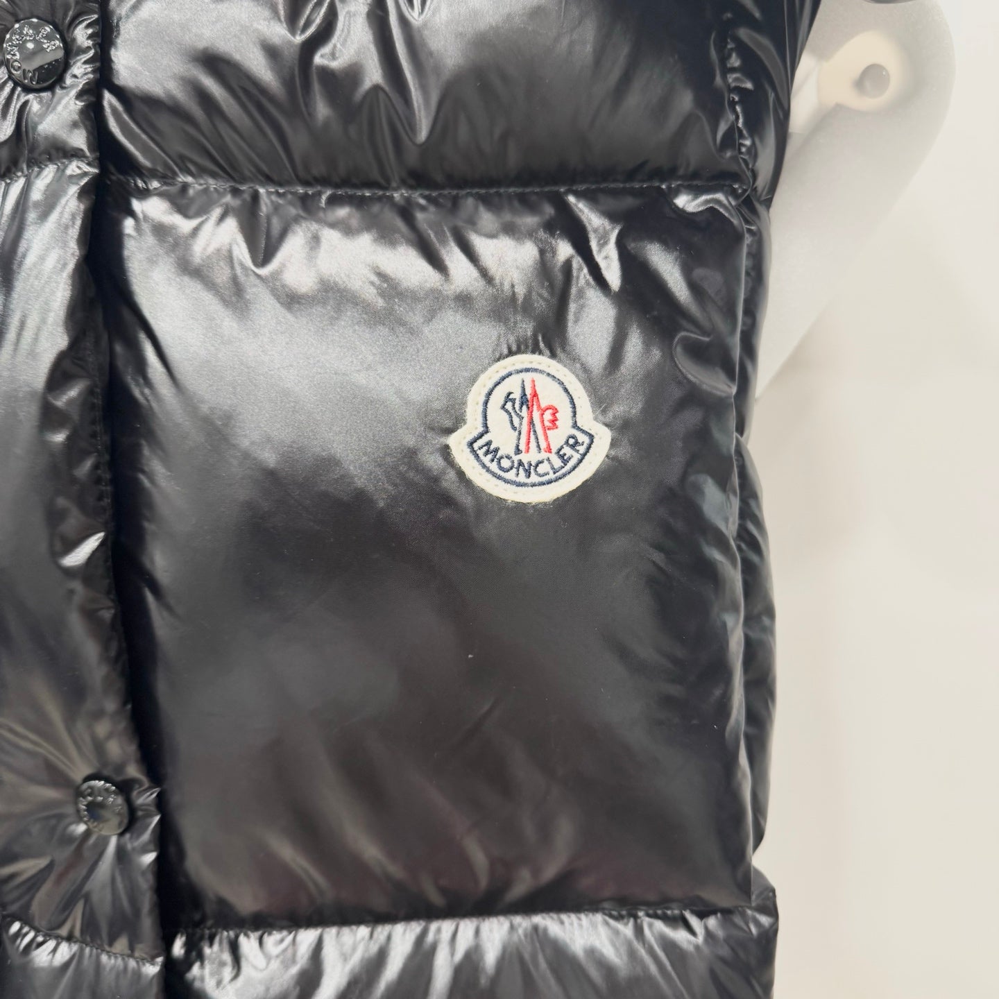 Moncler long puffer jacket front logo patch on shiny dark quilted fabric