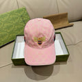 Pink baseball cap with GG-style monogram and gold-tone bee emblem at front