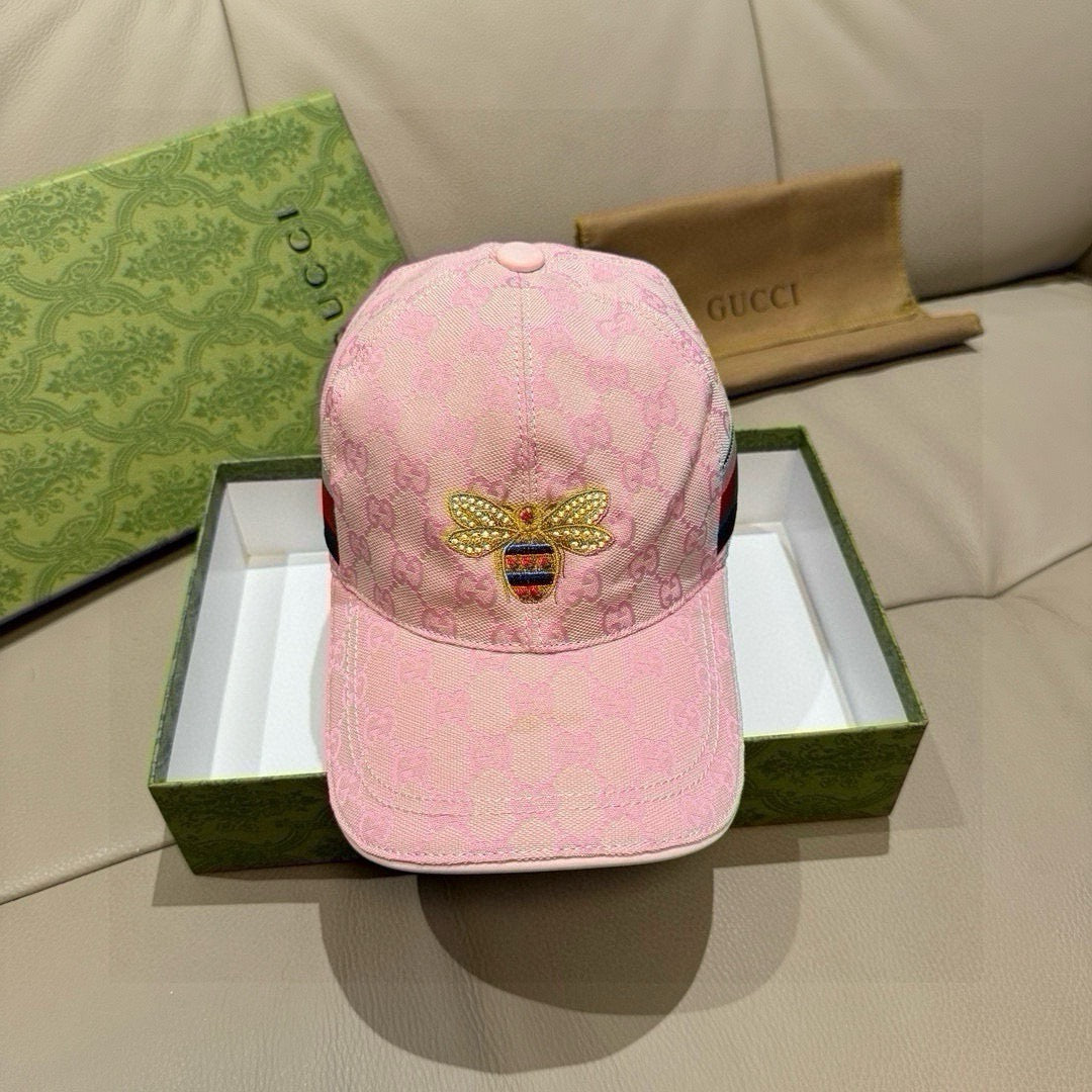 Pink baseball cap with GG-style monogram and gold-tone bee emblem at front
