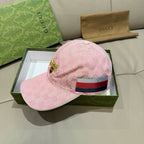 Pink baseball cap with monogram pattern, curved brim, and multicolor striped strap