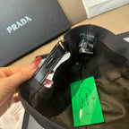 Prada baseball cap, black with adjustable strap and green product tag detail.