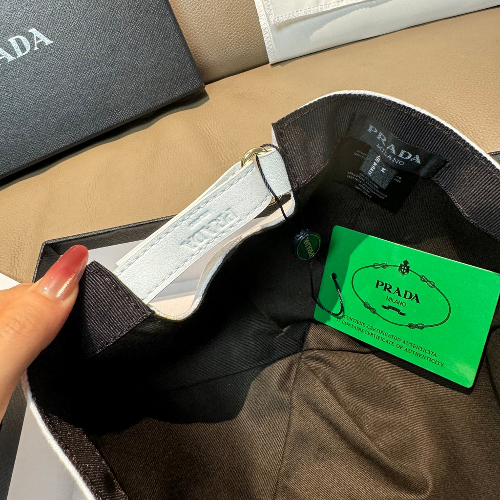 White Prada cap inside view with black lining and green PRADA authenticity tag.