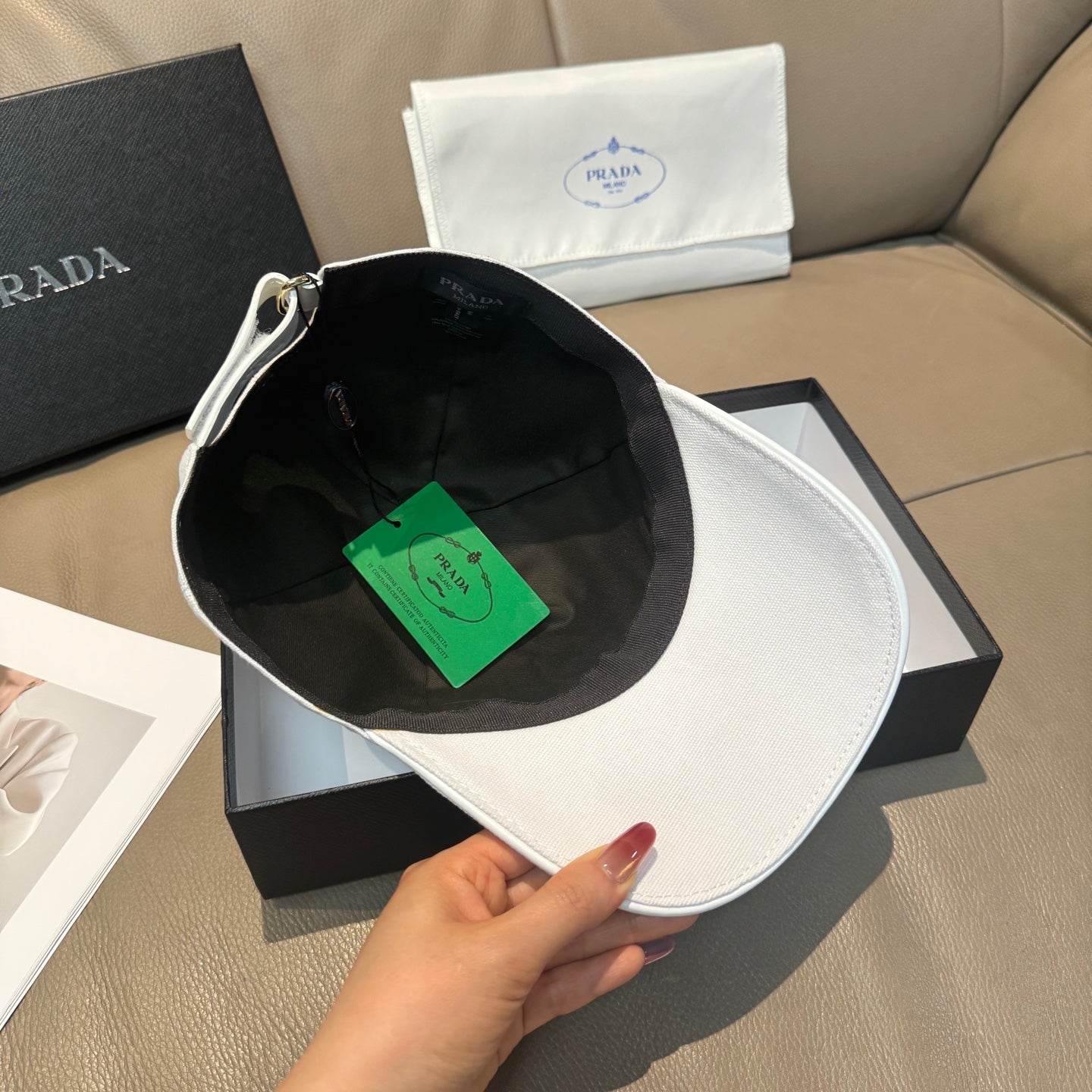 White Prada cap with black interior lining and front embroidery, curved brim.