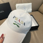 White Prada cap with embroidered PRADA MILANO text and small green leaf detail.