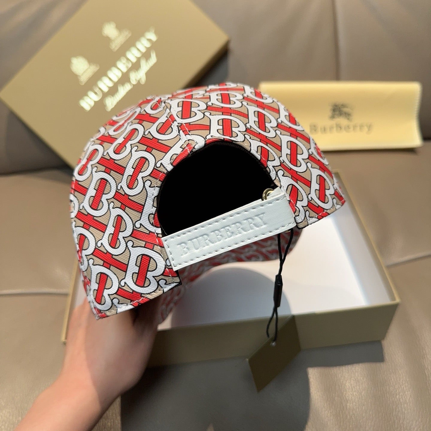 Baseball cap with red and white TB monogram pattern, white strap detail.