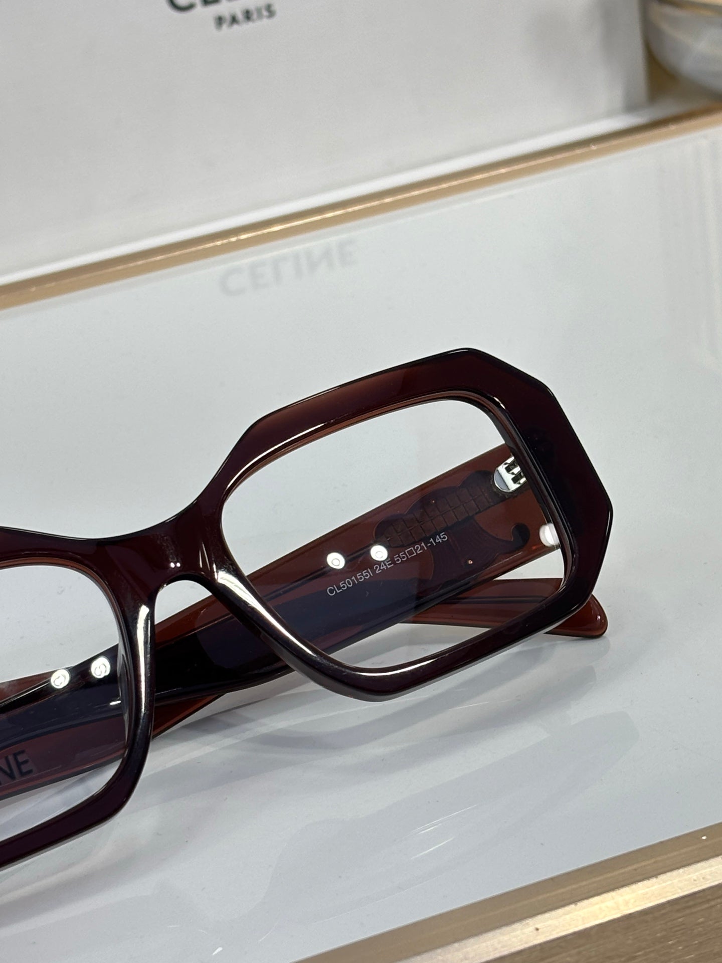 Celine glasses close-up, dark maroon square frame with logo near temple