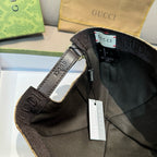 Black baseball cap with Gucci web stripe and hanging tags on the brim and strap.