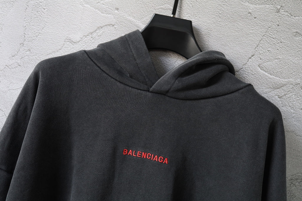 Balenciaga hoodie close-up in dark gray with hood and small red BALENCIAGA logo