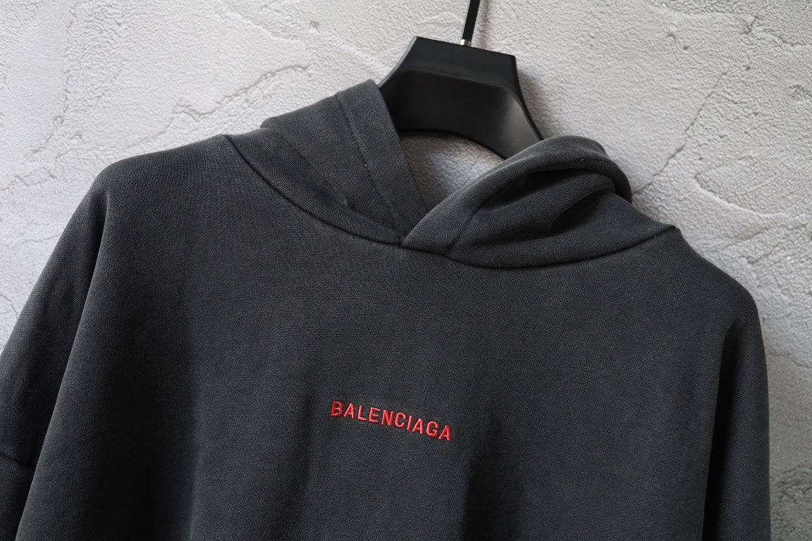 Balenciaga hoodie close-up in dark gray with hood and small red BALENCIAGA logo