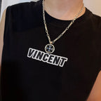 Chrome pendant necklace worn: round medallion with blue cross on silver chain