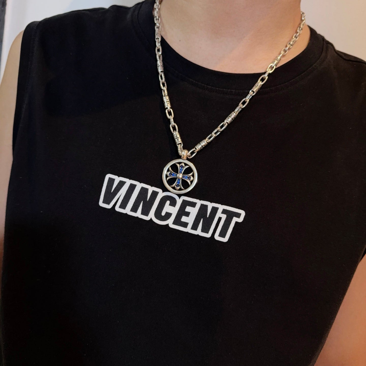 Chrome pendant necklace worn: round medallion with blue cross on silver chain