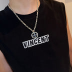 Chrome pendant necklace worn: small round blue cross medallion on silver chain
