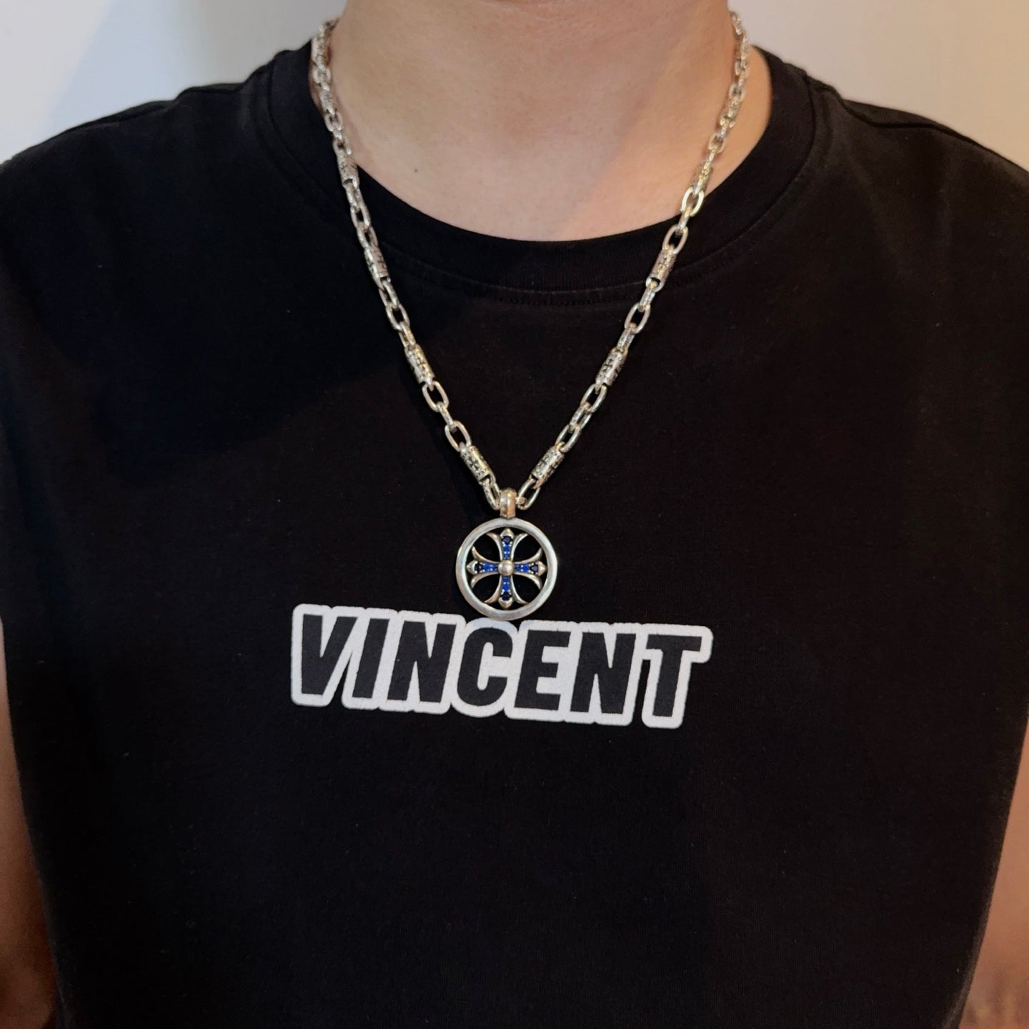 Chrome pendant necklace with round medallion and blue cross on a silver chain