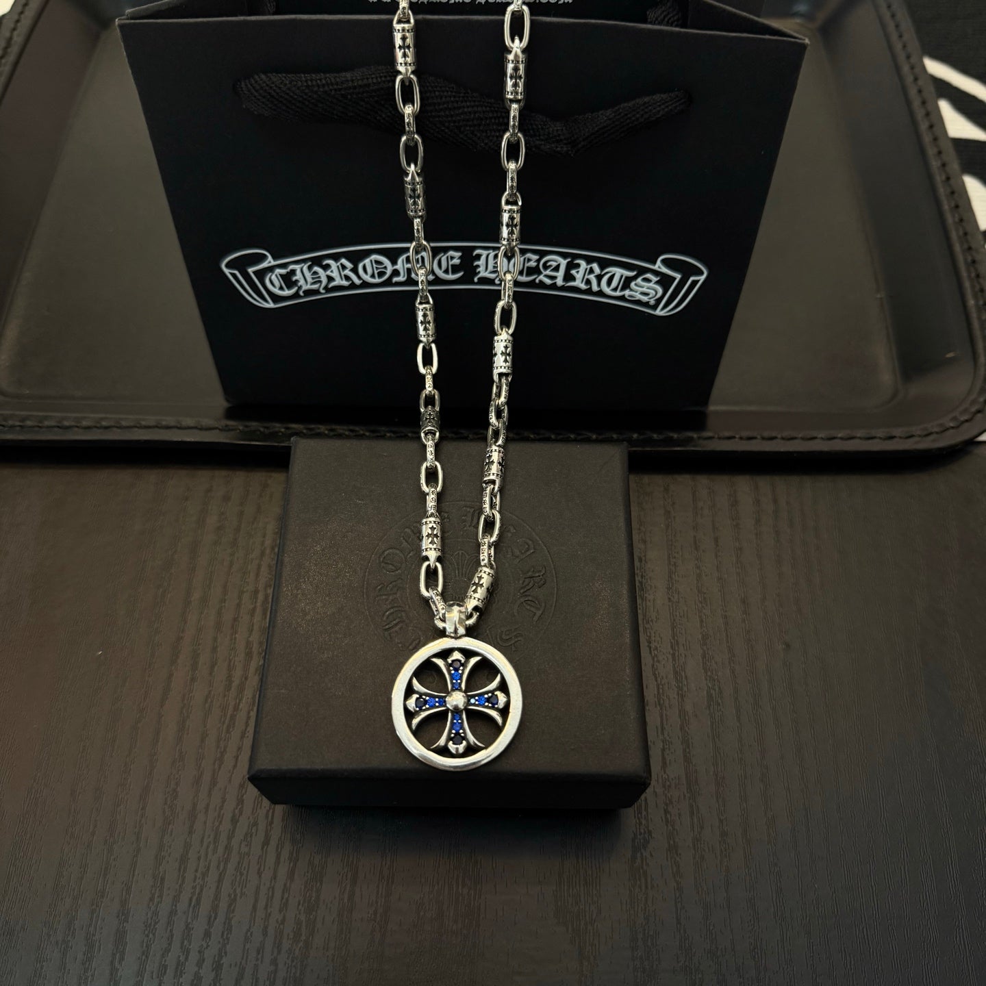 Chrome cross pendant necklace with blue accents in a round silver frame