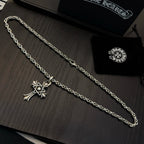 Chrome cross pendant necklaces with long linked chains, laid on a display surface