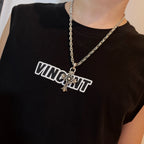 Chrome pendant necklace with star-and-cross charm worn on a dark crewneck shirt