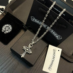 Chrome cross pendant necklace with star charm, shown on a gift box
