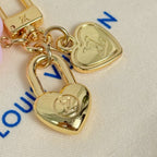 Gold heart and lock charms with blue logo marks on white pouch