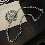 Silver chain necklace on black and cream pouches with embossed symbols