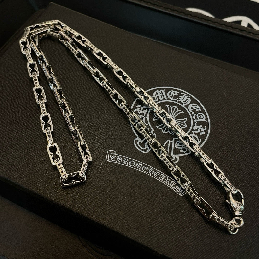 Silver chain necklace on jewelry box with ornate embossed emblem