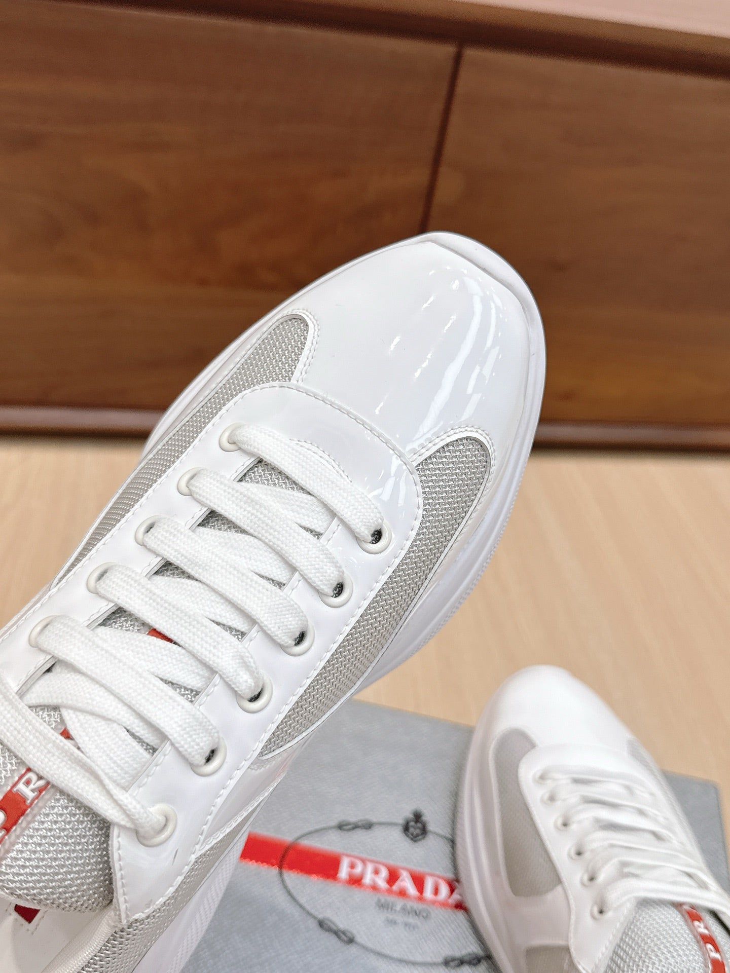 White sneaker close-up of toe and laces with textured mesh and glossy trim