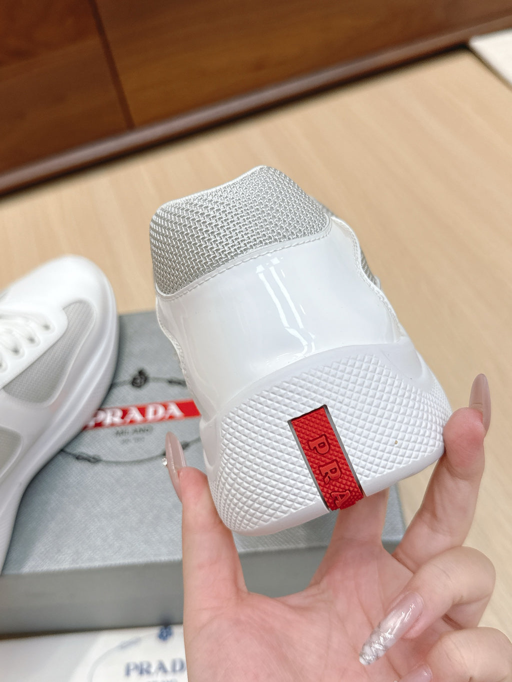 White sneaker heel with mesh back and red geometric logo patch
