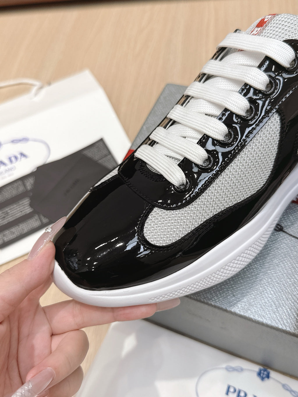 Prada unisex sneaker close-up: white mesh and black panels, white laces.