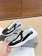 Prada unisex sneakers: black-and-white low tops with white laces and side stripe.