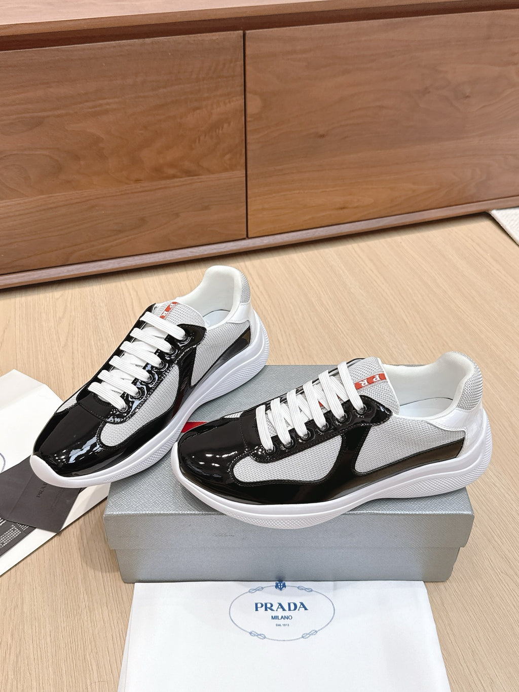 Prada unisex sneakers pair view: black and white uppers, white laces, white soles.
