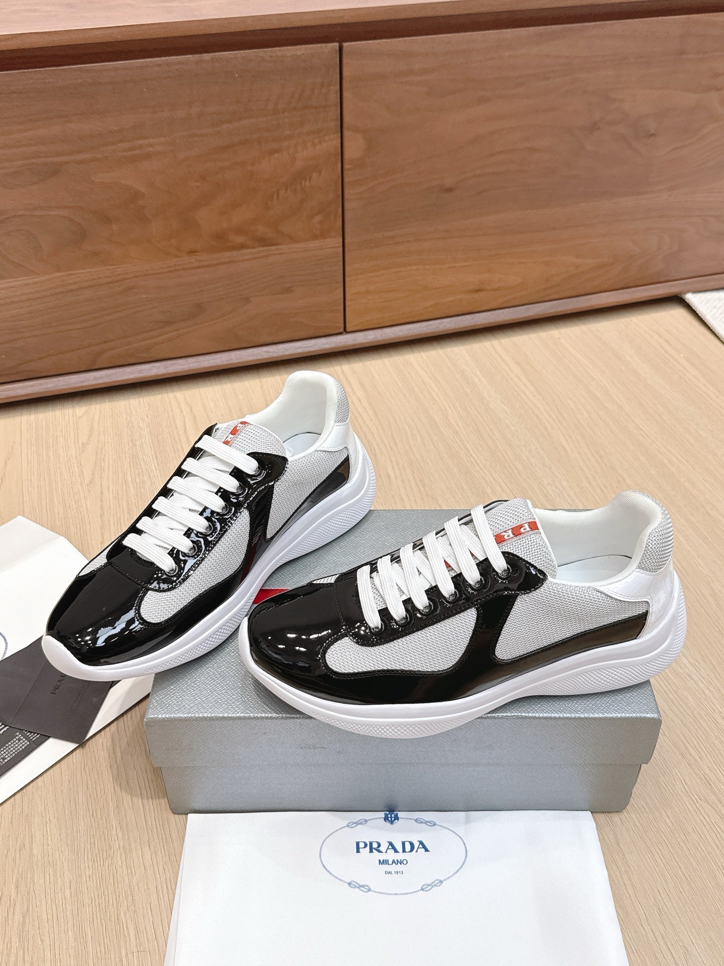 Prada unisex sneakers pair view: black and white uppers, white laces, white soles.