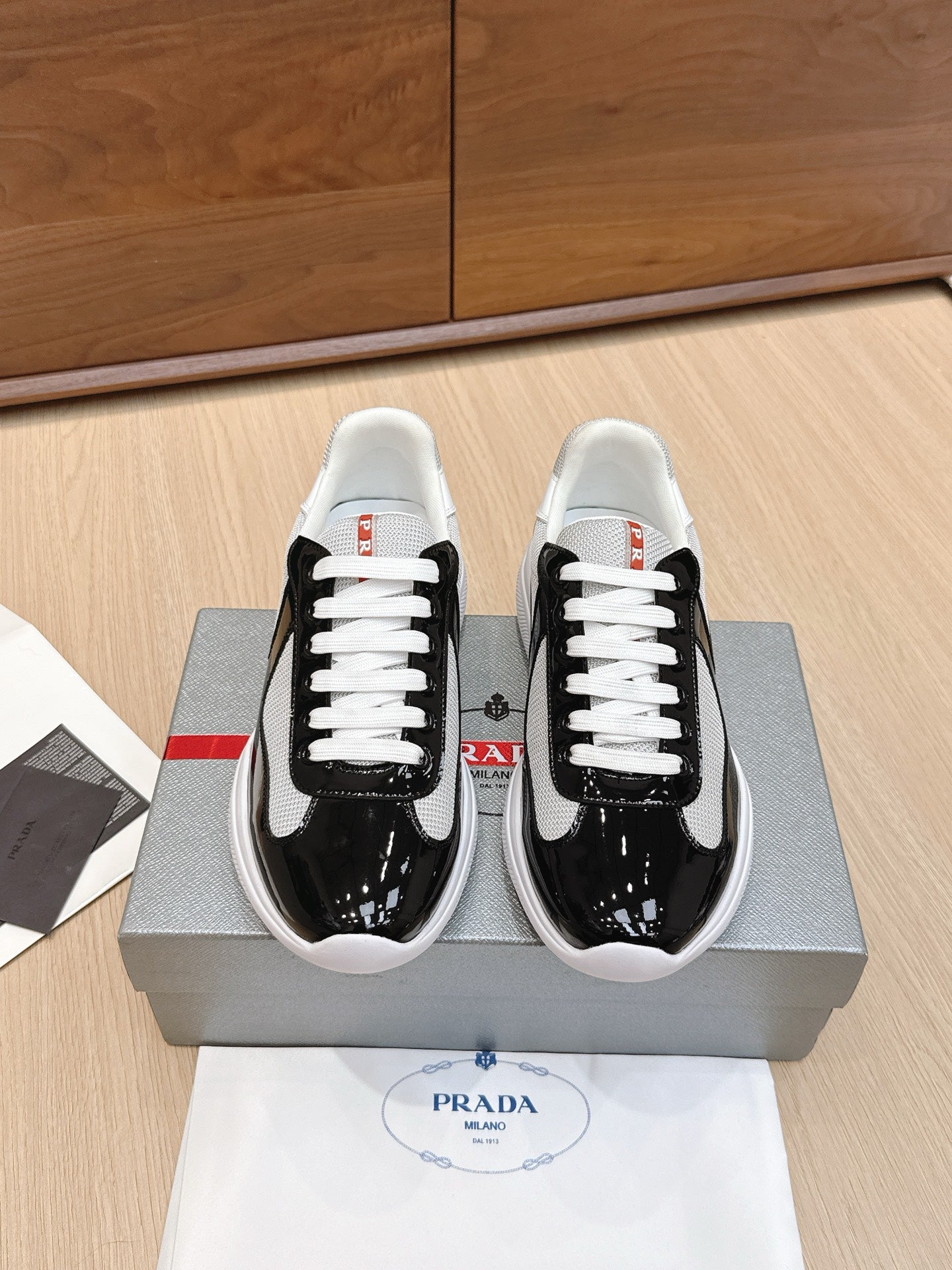 Prada unisex sneakers: black with white laces, white soles, black side stripe.