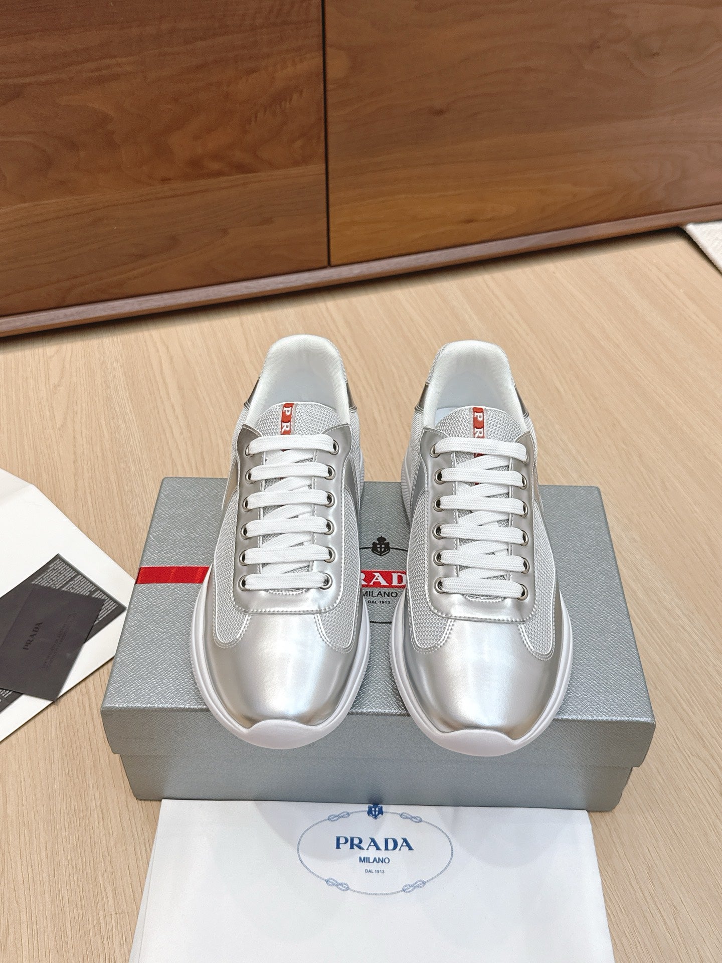 Unisex Prada sneakers in silver with white laces and red logo accents