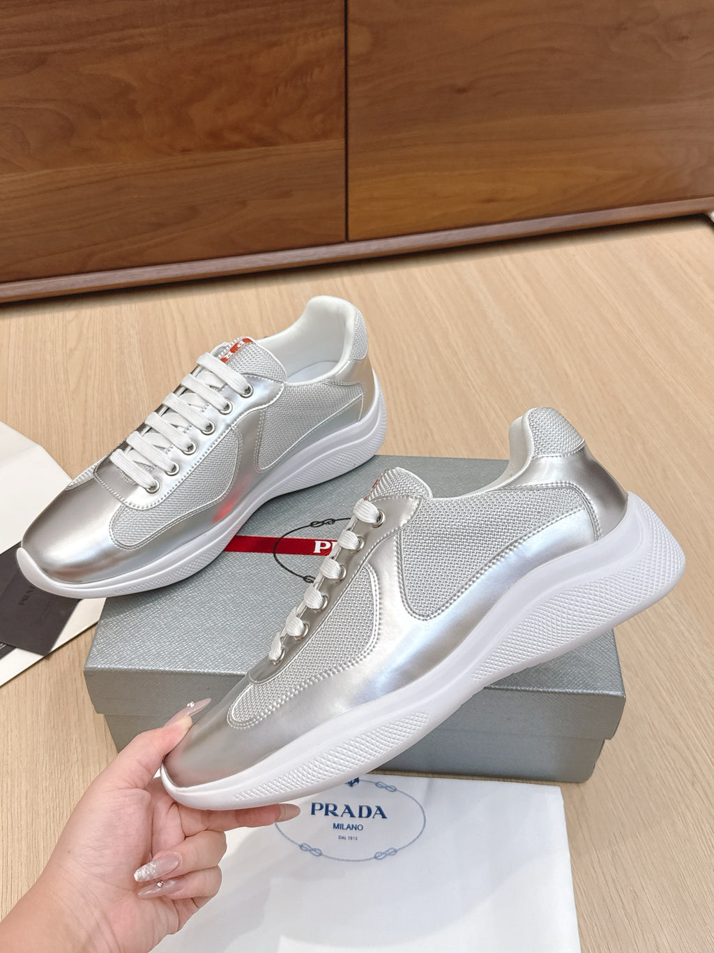 Unisex Prada sneakers with glossy silver finish and textured white outsole