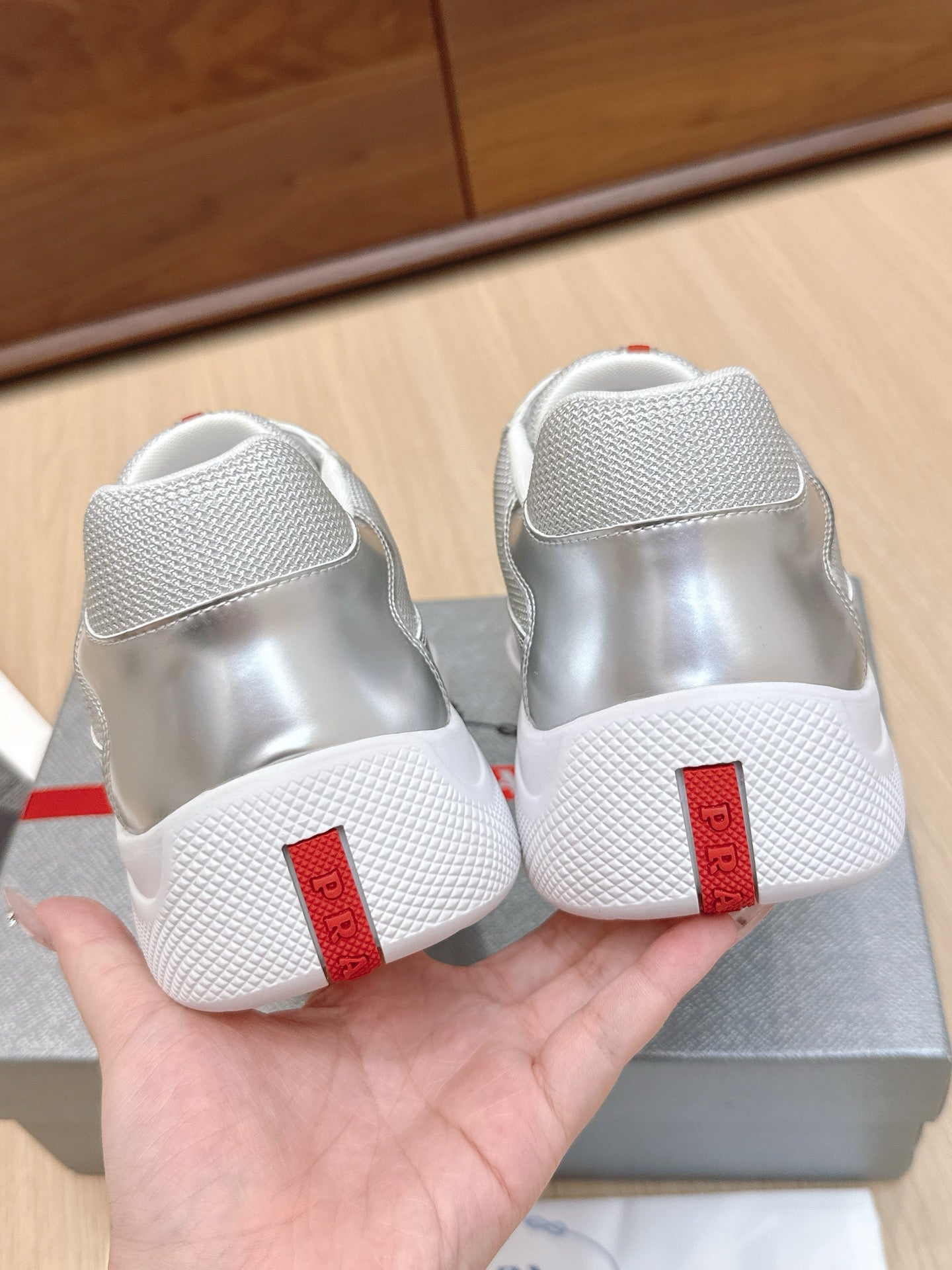 Prada unisex sneakers, rear view with red heel patch and textured white sole