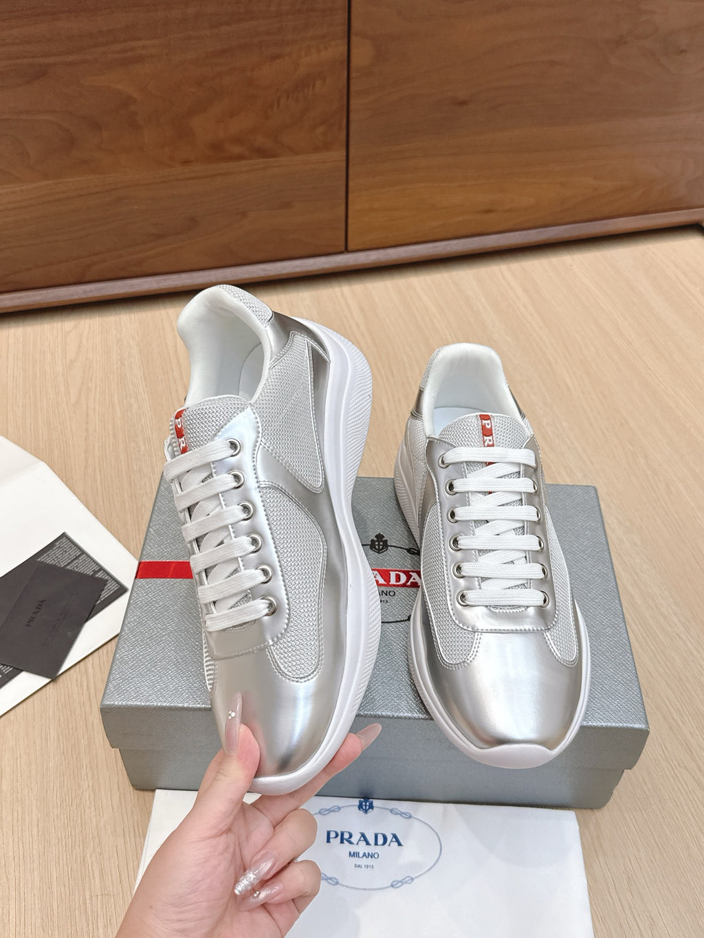 Prada unisex sneakers held up, silver-white leather with red heel logo